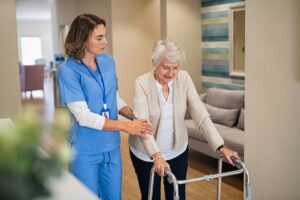 Older adult using a walker with assistance while boarding an accessible assisted living vehicle.